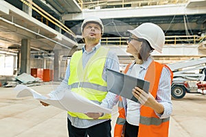 Building workers working at construction site, builders looking in blueprint. Building, development, teamwork and people concept