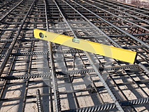 Building yellow colored level tool on the steel grid of residential building footing reinforcement