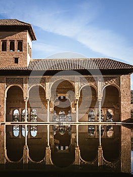 Buildings of the Alhambra Palaces in the El Partal part, reflection in the water pool, palm trees