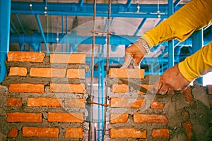 Buildings are built of hard red brick and are very long-lasting. Worker installing red brick for construction site. Buildings are