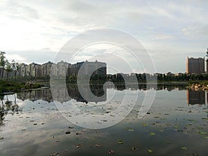 Buildings and clouds reflected in calm lake in the city. Reflection mirror