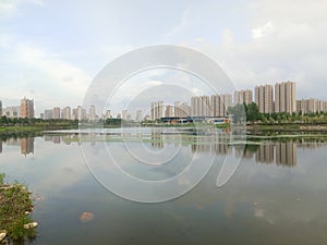 Buildings and clouds reflected in calm lake in the city. Reflection mirror