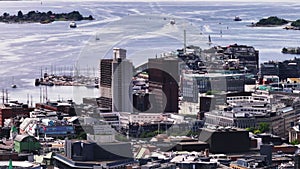 Buildings in coastal borough. Functionalistic City hall partially covered with scaffolding and sailboats in marina. Oslo