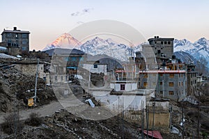 Buildings of Muktinath village and snowy peaks against dawn sky, Annapurna circuit, Nepal
