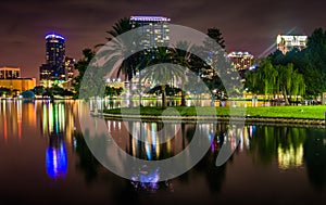 Buildings and palm trees reflecting in Lake Eola at night, Orlando, Florida.