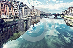 Buildings and Ponte Santa Trinita mirrored in river Arno, Florence, Italy