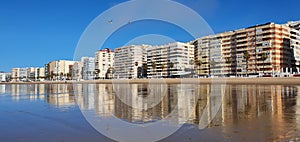 Buildings reflected in the wet sand on the shore of the beach in CÃ¡diz. photo
