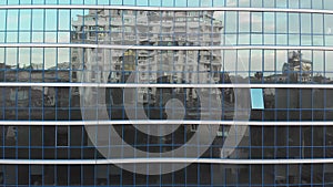 Buildings reflecting in the glass windows of the modern building, camera moves up