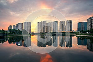 Buildings with reflections on lake at sunset at Thanh Xuan park. Hanoi cityscape at twilight period