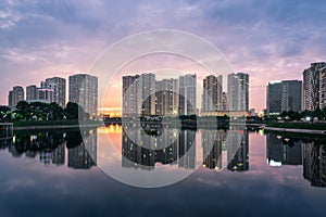 Buildings with reflections on lake at sunset at Thanh Xuan park. Hanoi cityscape at twilight period