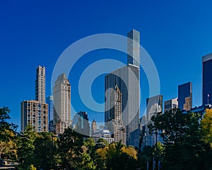 Buildings and skyscrapers of midtown Manhattan above trees, viewed from Central Park of New York City, USA