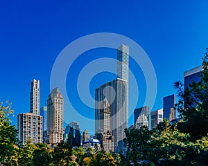 Buildings and skyscrapers of midtown Manhattan above trees, viewed from Central Park of New York City, USA