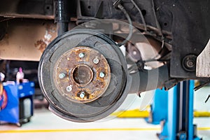 Buildup of rust on rear brake rotors cover on a car lift in garage