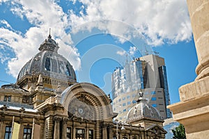 Built in 1900, CEC Palace in Bucharest, Romania in Romanian: Palatul CEC next to tall glass building with clouds reflected.