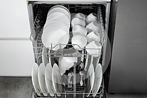 Built-in dishwasher. Clean dishes in the dishwasher. A clean white utensil. Modern technologies in the kitchen. Modern