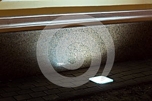 Built in ground lantern in stone tile illuminate granite facade.