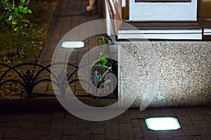 Built in ground lantern in stone tile illuminate granite facade.