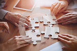 Buisnesswomen and buisnessmen working together while putting together puzzles.