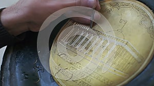 Bukhara master engraves patterns on a tray. Close up