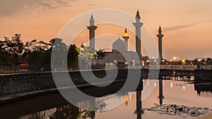 Bukit Jelutong Mosque in Malaysia with sunrise scene. Reflection of the mosque and beautiful Nymphaea on the lake.