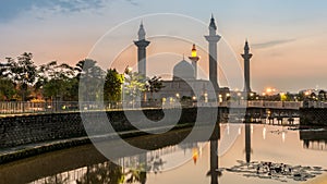 Bukit Jelutong Mosque in Malaysia with sunrise scene. Reflection of the mosque and beautiful Nymphaea on the lake.