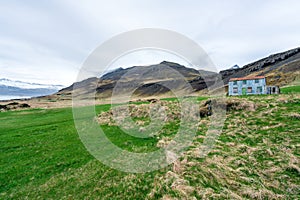 Bulandstindur mountain peak with snow on it. Blue abandoned farmhouse infront of it.