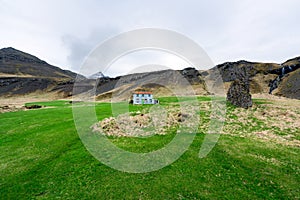 Bulandstindur mountain peak with snow on it. Blue abandoned farmhouse infront of it.