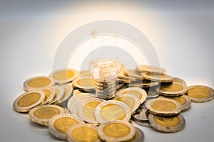 The bulb is placed stack of coins, the bulb is lit in darkness. Image use for finding a way out in the dark