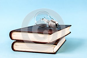 Bulb on two closed books isolated on a blue background