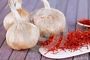 Bulbs of crocus sativus, dry spice saffron in wooden spoon on a wooden background photo