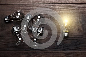 Bulbs uniqueness concept on wooden background photo