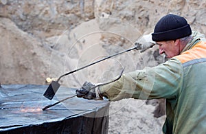 Bulder during waterproofing works with blowpipe torch photo