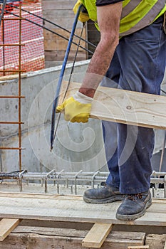 Bulder worker sawing wood board with hand saw 2