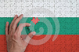 Bulgaria flag is depicted on a puzzle, which the man`s hand completes to fold