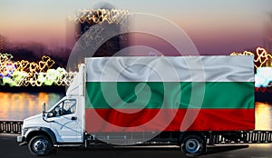 Bulgaria flag on the side of a white van against the backdrop of a blurred city and river. Logistics concept