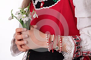 Bulgarian girl in traditional folklore costumes with snowdrop flowers, martenitsa symbol of Baba Marta, spring, Easter holiday
