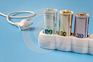 Bulgarian lev banknotes plugged into a white power strip over blue background. Increasing cost of electricity in Bulgaria. Rise in