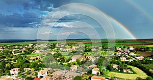 Bulgarian village in the countryside and beautiful bulgarian nature and agriculture fields, aerial panorama view with rainbow