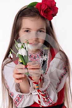 Bulgarian woman with bouquet spring snowdrop flowers and martenitsa March holiday Baba Marta, Bulgaria