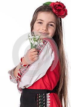 Bulgarian woman in ethnic costume with bouquepring snowdrop flowers and martenitsa Baba Marta. Bulgaria