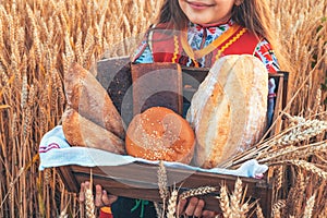 Bulgarian woman  or young girl in traditional folklore dress holds in hands golden wheat and freshly baked homemade bread in a bag