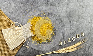 bulgur, cereal made from boiled, dried and crushed wheat. grains poured out of a bag on a dark background. upper view