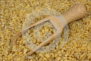 Bulgur or couscous scattered with a wooden scoop