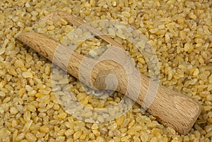 Bulgur or couscous scattered with a wooden scoop