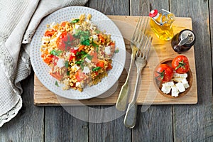 Bulgur with roasted peppers, tomatoes, parsley and feta cheese on a wooden background. Vegetarian dish. Selective focus. Top view