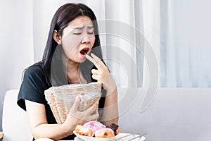 Bulimia nervosa, anorexia nervosa concept with Asian woman put her fingers in her mouth and holding bin in hand try to vomit after