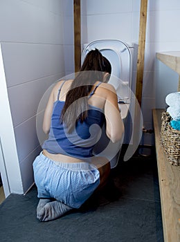 Bulimic woman feeling sick guilty fingers in mouth vomiting and throwing up in WC toilet