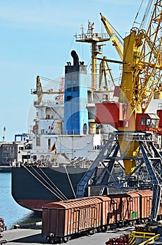 Bulk cargo ship and train under port crane