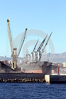 The bulk-carrier LAWIN ARROW loading cement with cranes in the port of Alicante.