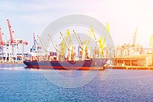 Bulk carrier ship in the port on loading. Bulk cargo ship under port crane bridge.